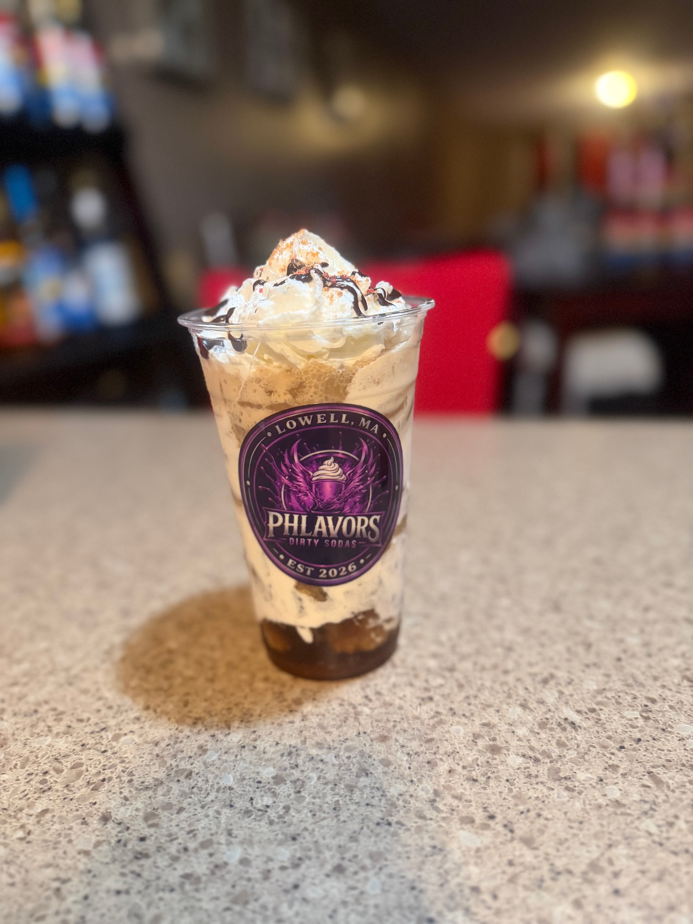 Phlavors branded cup with whipped cream and chocolate drizzle