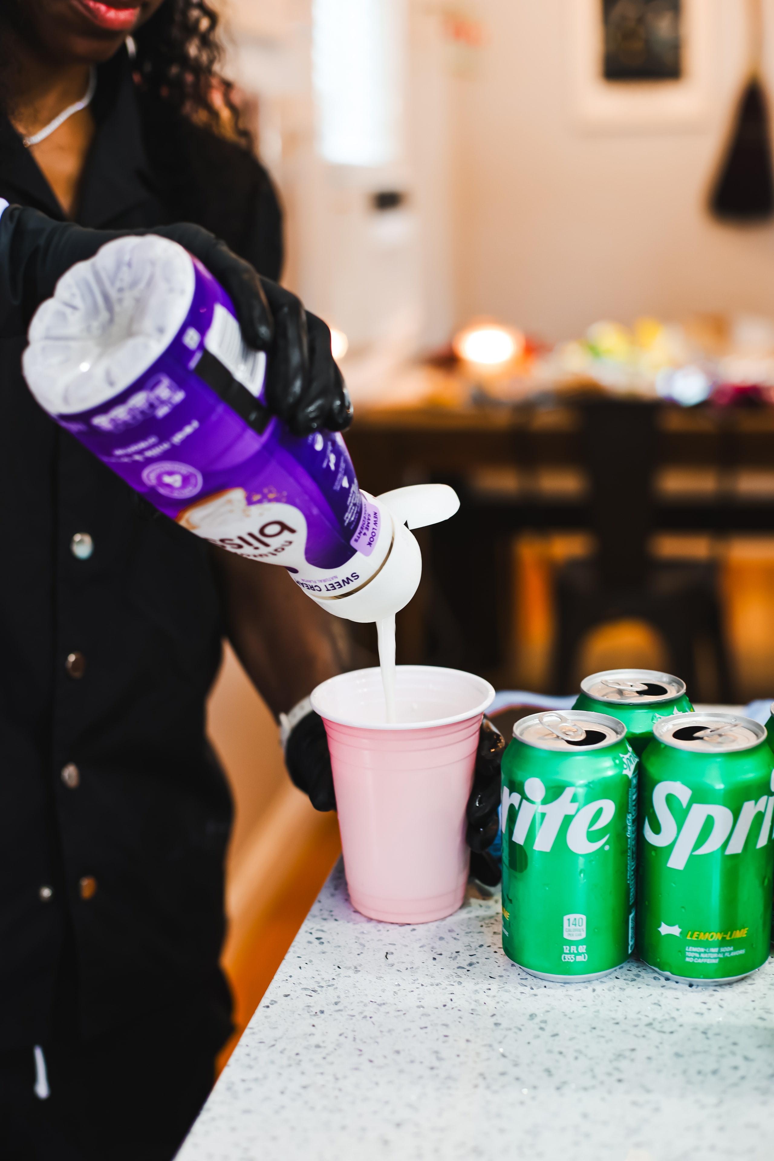 Sweet cream being poured into a cup with Sprite cans nearby